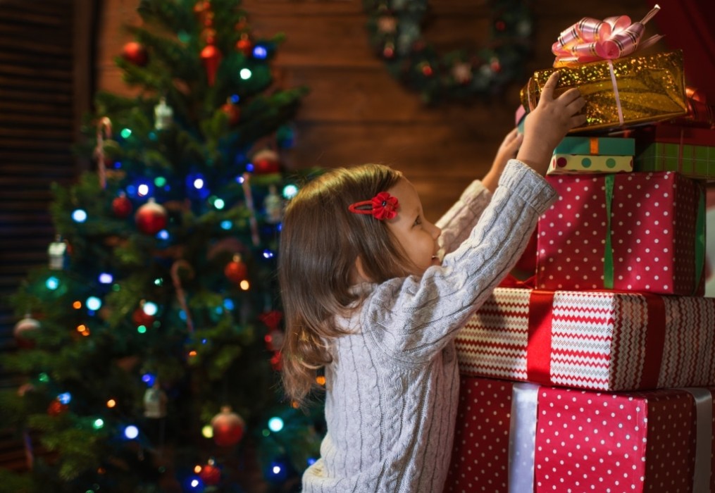 girl at home with a Christmas tree, presents and candles celebrating christmas