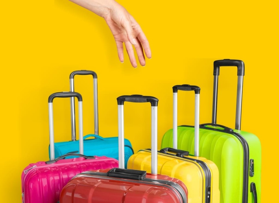 Female hand holds a suitcase on a bright yellow background
