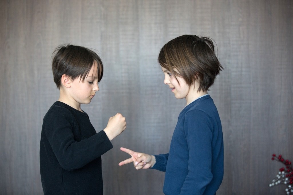 Two children, boy brothers, playing rock scissors paper game