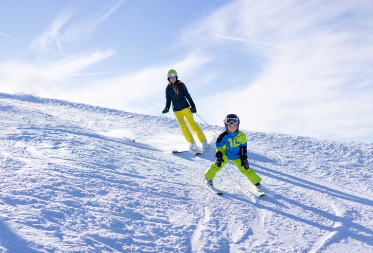 Kind mit Mutter beim Skifahren