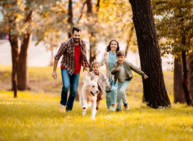 Glückliche Familie läuft im Urlaub einen Hund hinterher